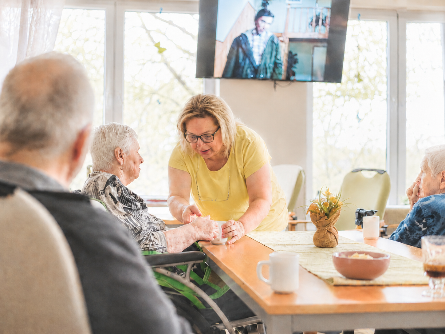 A care worker supporting older adults with calm, person-centred dementia care