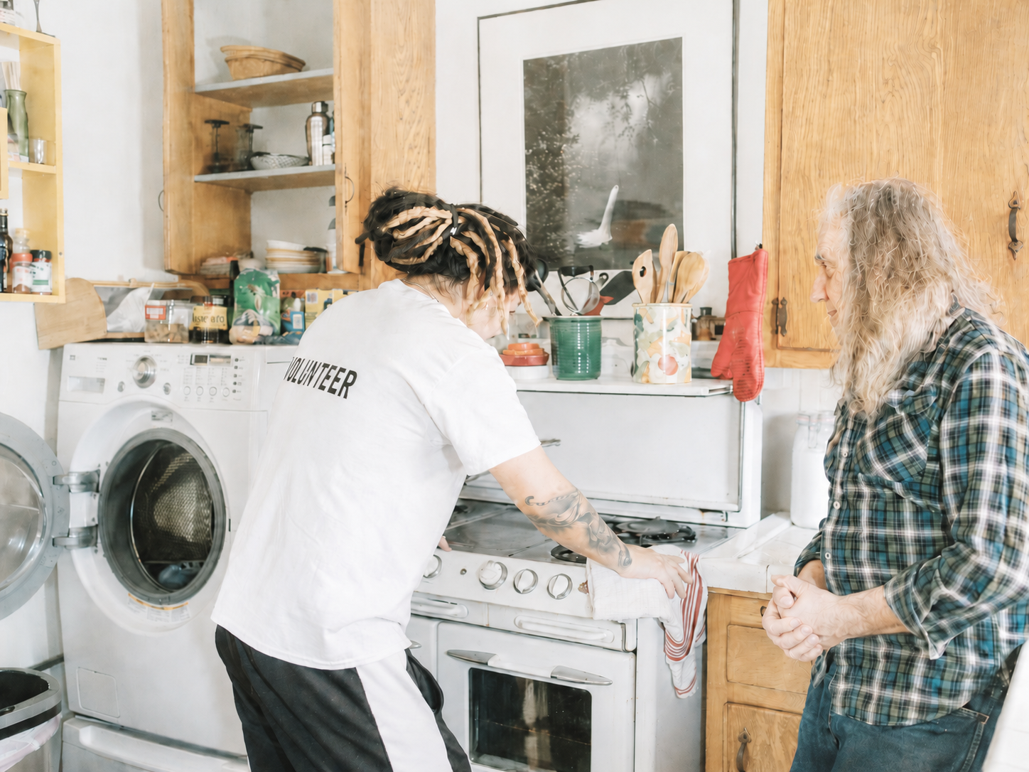 A care worker helping an older client with practical household support in a home kitchen
